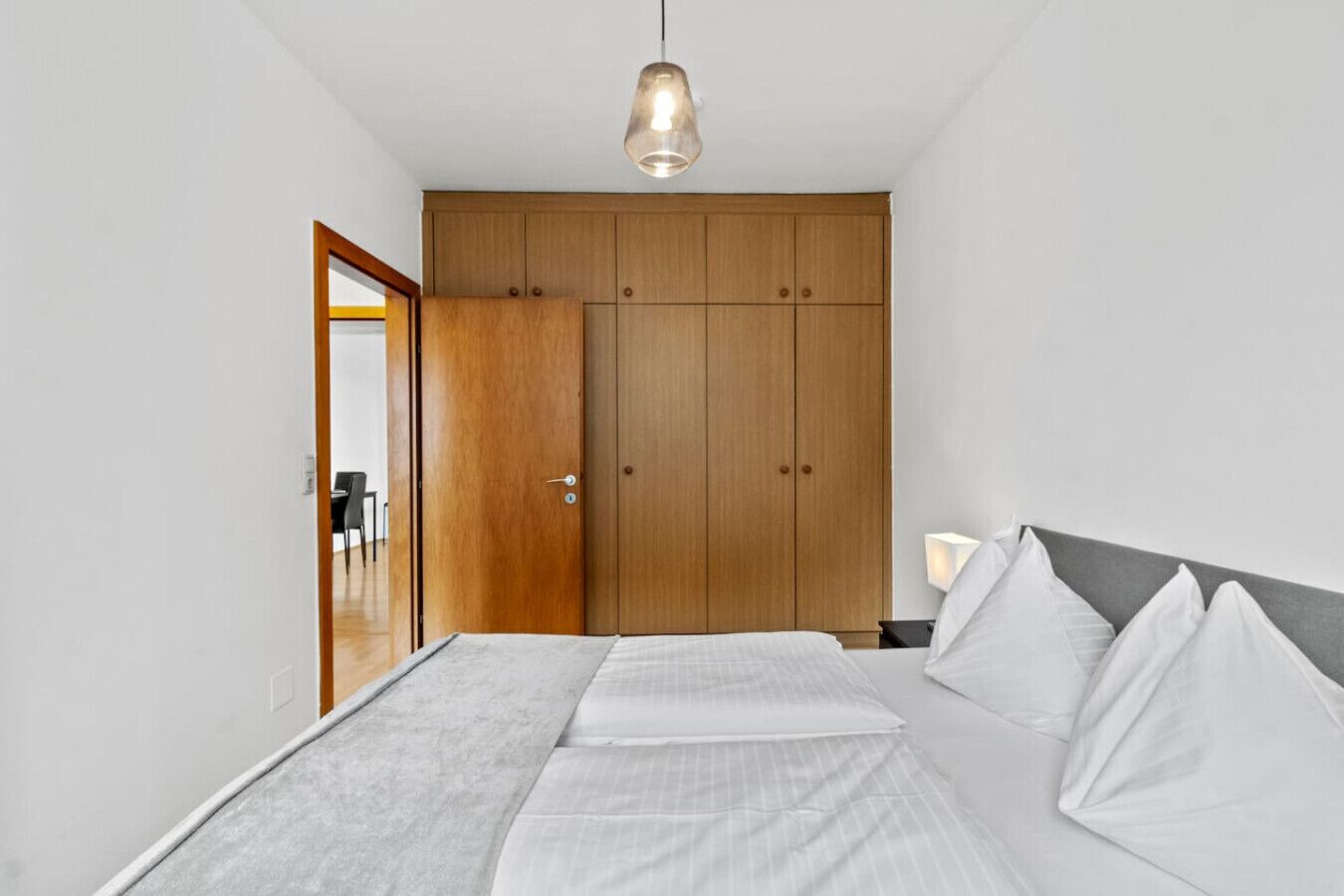 Een slaapkamer met een bed, een kledingkast en een hanglamp.