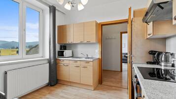 Une cuisine moderne avec des meubles en bois, un four à micro-ondes, une bouilloire et une vue sur l’extérieur.