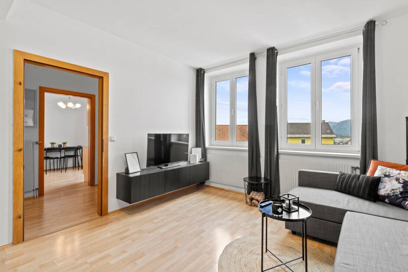 Een moderne woonkamer met een bank, televisie en een eethoek.
