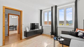 Een moderne woonkamer met een bank, televisie en een eethoek.
