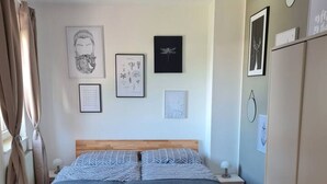 Een slaapkamer met een houten bed, een wit vloerkleed en diverse ingelijste foto’s aan de muur.