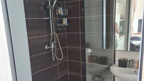 Een moderne badkamer met een douchecabine van glas, een wastafel en een spiegel.