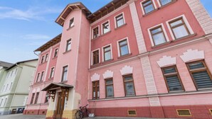 A multi-story building with a pink facade, a wooden door, and a bicycle parked in front. - FarawayHomes Studio Saint Michael #10 (Liesingtal)