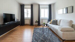 Un salon moderne avec un téléviseur à écran plat, un canapé, une petite table d’appoint et un tapis.