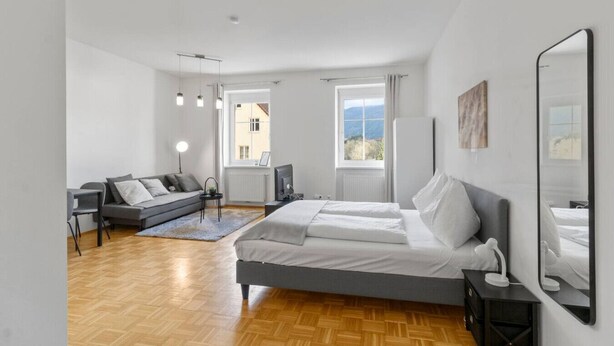 Een moderne slaapkamer met een bed, een bank, een bureau en een raam met uitzicht.