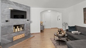 A modern living room with a fireplace, a sofa, a coffee table, and a TV mounted on the wall. - FarawayHomes Studio Bruck #3 (Bruck an der Mur)