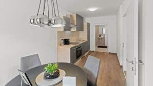 A modern kitchen with a dining area, featuring a round table, chairs, and a pendant light. - FarawayHomes Studio Bruck #3 (Bruck an der Mur)