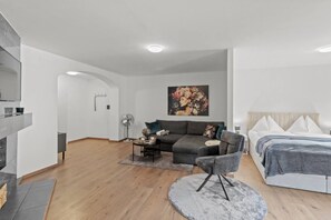 Una habitación de hotel moderna con un sofá, una mesa redonda, una cama y un cuadro en la pared.