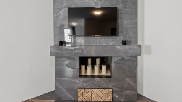 A modern fireplace with a flat-screen TV mounted above it. - FarawayHomes Studio Bruck #3 (Bruck an der Mur)