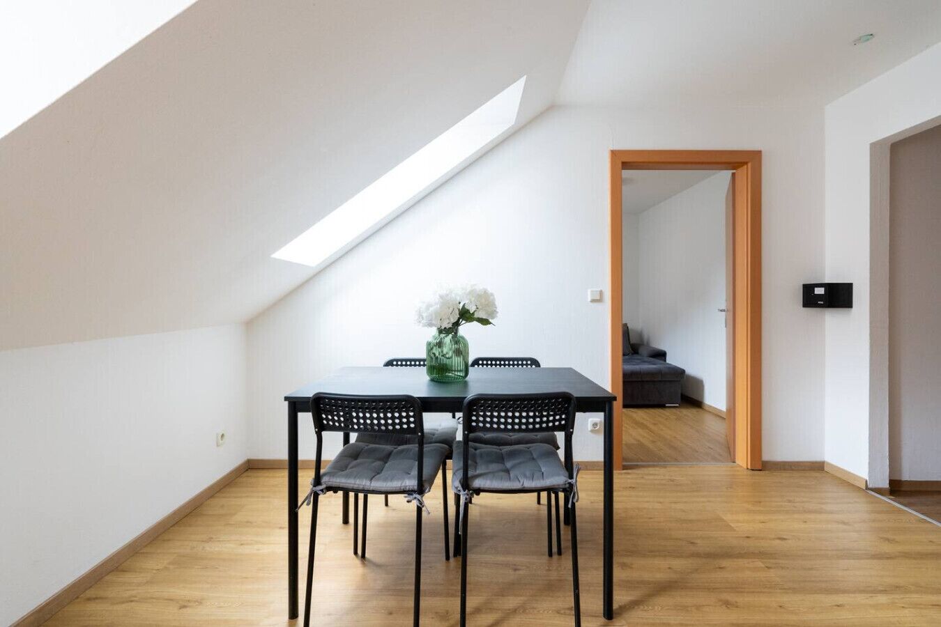 Un coin repas avec une table, des chaises et un vase de fleurs.
