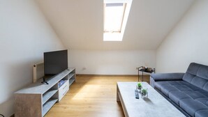 A modern loft apartment with a sloped ceiling, a built-in TV, a gray sofa, a coffee table, and a skylight. - FarawayHomes Studio Graz #6 (Graz)