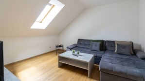 A loft-style living room with a sloped ceiling, a sectional sofa, a coffee table, and a skylight. - FarawayHomes Studio Graz #6 (Graz)