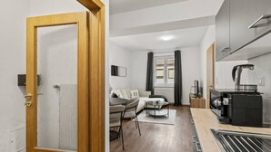 A compact living space with a kitchenette, a sofa, a dining table, and a window with curtains. - FarawayHomes Studio Fohnsdorf #4 (Fohnsdorf)