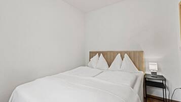 Una habitación de hotel con una cama, una mesita de noche y una lámpara.