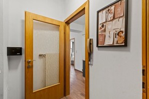 A hallway with a wooden door, a wall-mounted phone, and a framed photo collage. - FarawayHomes Studio Fohnsdorf #4 (Fohnsdorf)