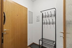 Ein Zimmer mit Holztür, einem Metallkleiderhaken und einer kleinen Ablagefläche.