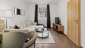 A modern living room with a sofa, a coffee table, a TV, and a wooden cabinet. - FarawayHomes Studio Fohnsdorf #4 (Fohnsdorf)