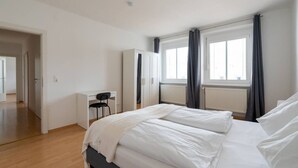 A bedroom with a bed, a desk, and a wardrobe.