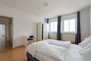 Ein Schlafzimmer mit Bett, Schreibtisch, Stuhl und Kleiderschrank.