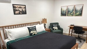 A bedroom with a wooden bed, a desk, a chair, and wall art.
