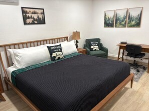 Quarto com cama de madeira, escrivaninha, cadeira e obras de arte nas paredes.