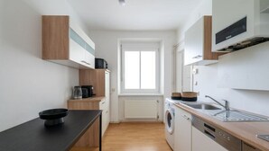 Ett kompakt kök med tvättmaskin, kaffebryggare och diskho.