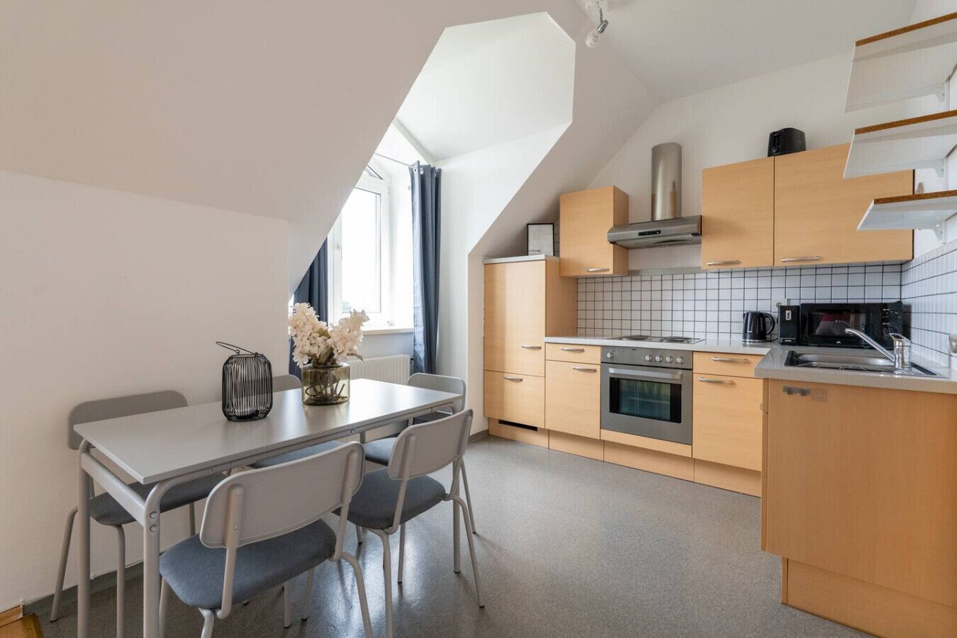 A modern kitchen with a dining area, featuring a stove, oven, microwave, and a small sink.