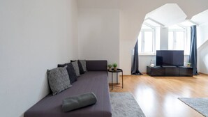 Un salon moderne avec un canapé, un téléviseur et une petite table agrémentée de plantes.