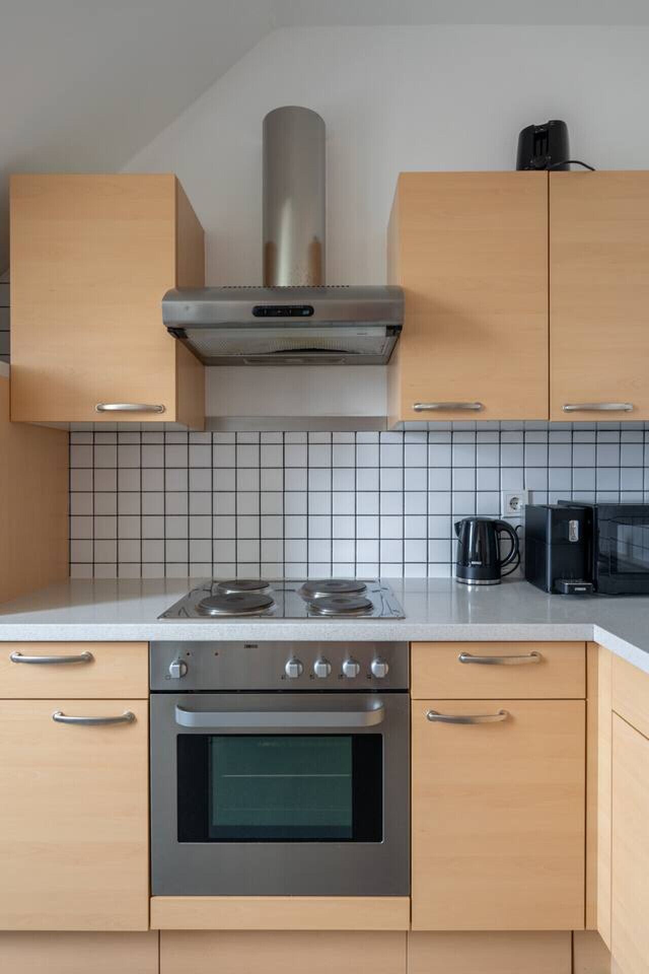 A modern kitchen with a stove, oven, microwave, and coffee maker.
