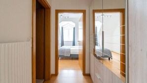 Un couloir étroit mène à une chambre dotée d’un grand miroir et d’un lit.