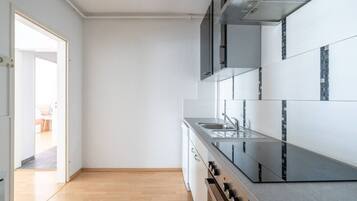 A modern kitchen with a stainless steel sink, a built-in oven, and a view into the adjacent living area.