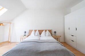 A bedroom with a bed, bedside tables, a wardrobe, and a skylight.