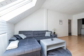 A modern loft-style living room with a gray sectional sofa, a small coffee table, and a skylight.