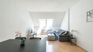 Un appartement moderne de style « loft », comprenant un coin repas, un salon avec un canapé et une table basse, et une grande verrière.