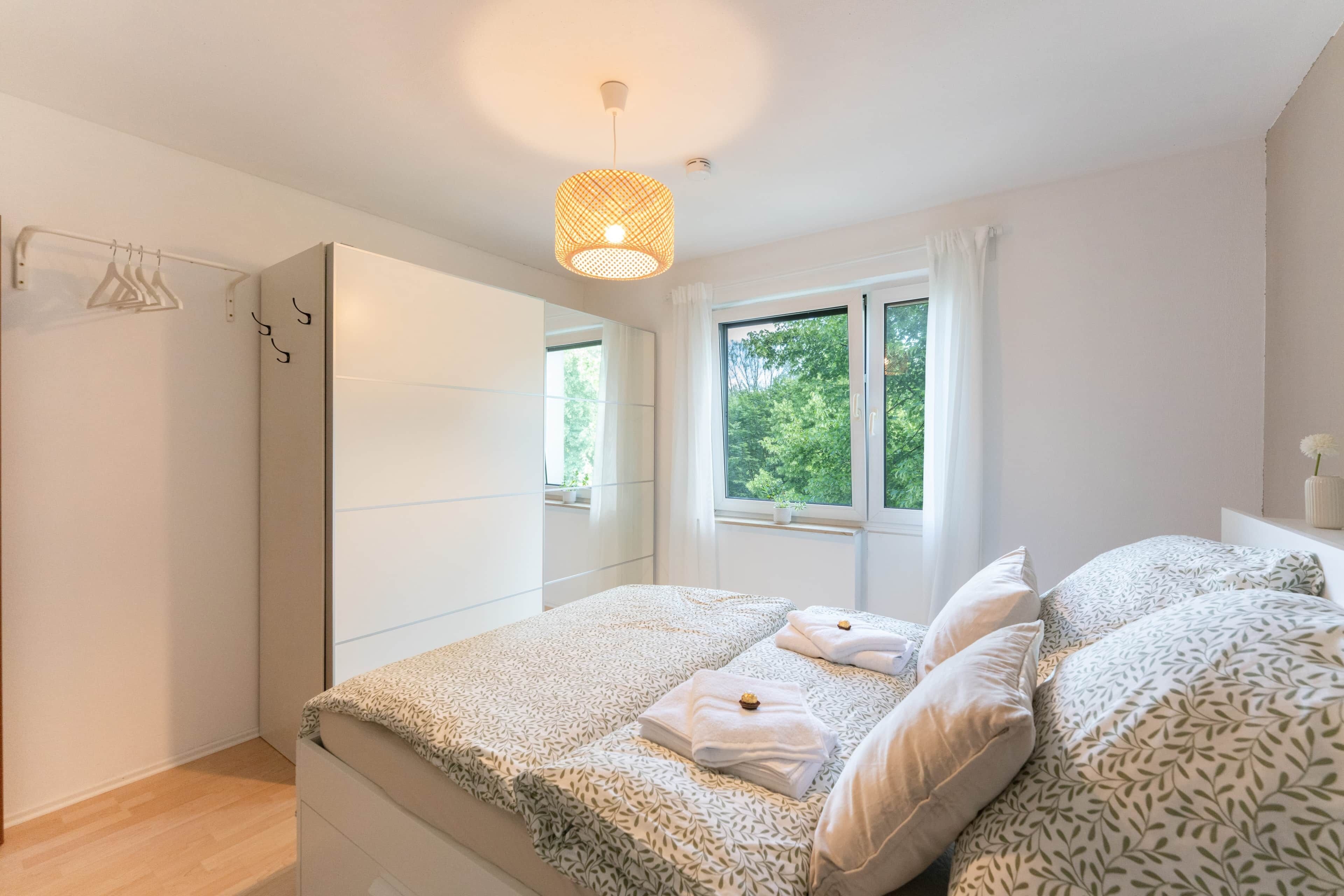 Une chambre à coucher avec un lit, une fenêtre, une armoire et un luminaire suspendu.