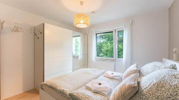 Une chambre à coucher avec un lit, une fenêtre, une armoire et un luminaire suspendu.