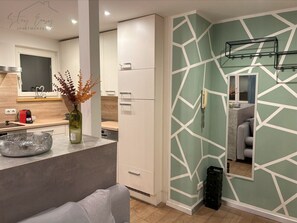A modern kitchen with a white cabinet, a vase with dried flowers, and a mirror on the wall.