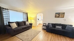 A living room with two sofas, a rug, and a kitchen in the background.
