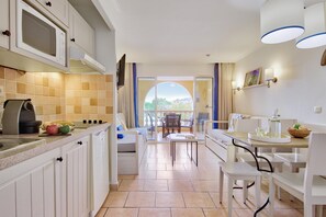 Una cocina con microondas, cafetera y comedor con mesa y sillas.