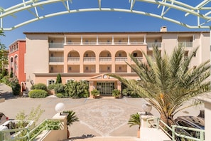 Un hotel de varios pisos con un patio central, balcones y palmeras.