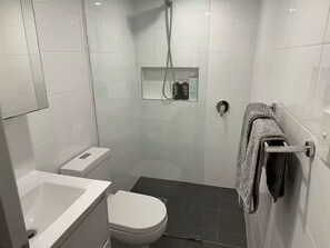 Une salle de bain moderne équipée de toilettes, d’un lavabo et d’une douche.
