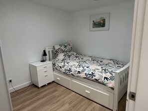 A bedroom with a bed, a nightstand, a lamp, and a picture on the wall.