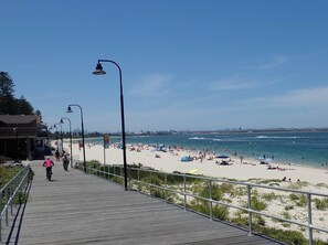 A wooden boardwalk leading to a beach with a clear sky.