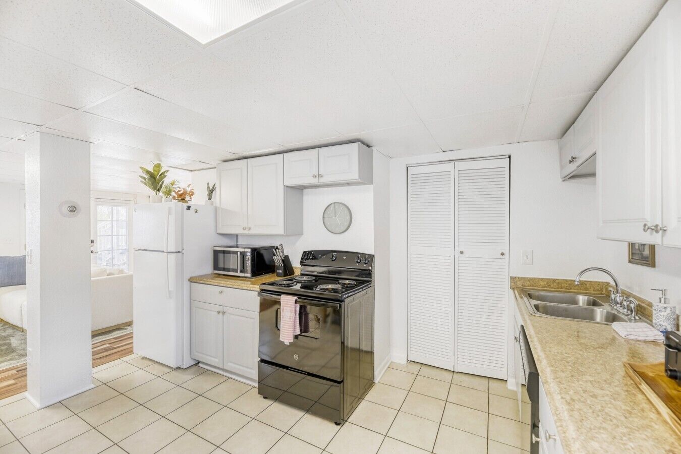 A kitchen with white cabinets, a stove, a microwave, and a sink.