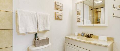 A bathroom with a toilet, sink, mirror, and towels.