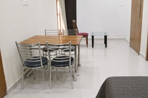 A dining area with a wooden table and metal chairs, a glass-top table, and a red chair.