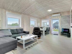Ein modernes Wohnzimmer mit einer Couch, einem Couchtisch und einem Essbereich mit Stühlen und einem Tisch.