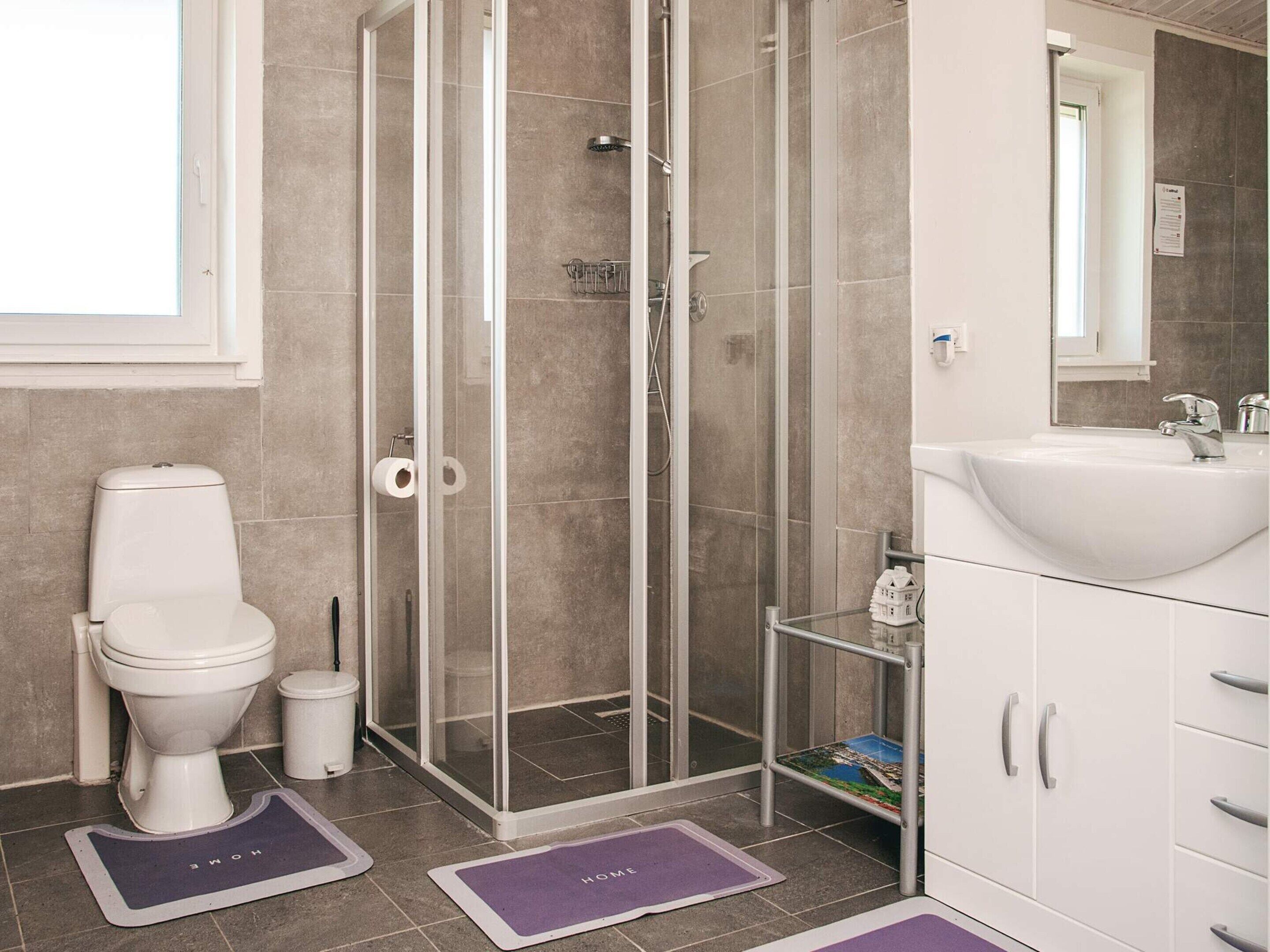 Een moderne badkamer met toilet, douche en wastafel.