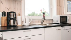 Ett modernt kök med kaffebryggare, vattenkokare, mikrovågsugn och en diskho.