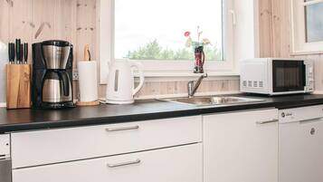 A modern kitchen with a coffee maker, kettle, microwave, and a sink.